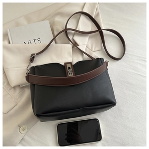 Close-up of black crossbody bucket bag with brown handle and silver metal hardware