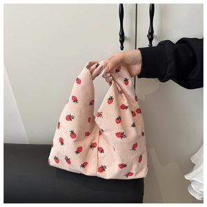 Détail d'un sac à main en velours côtelé rose avec motifs fraises et texture douce