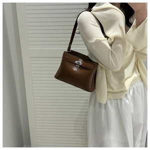 Close-up of brown leather handbag with silver turn-lock and classic vintage structure