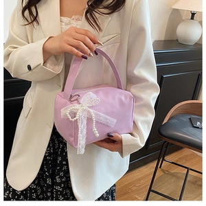 Detail of lavender handbag featuring delicate white lace trim and beaded bow pendant