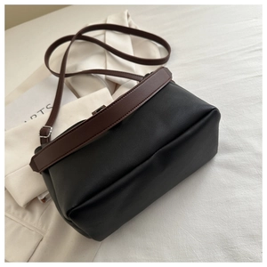Top-down view of a vintage black and brown leather crossbody bag on minimalist prop background