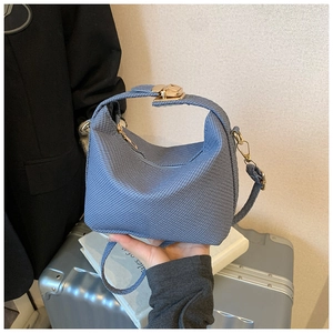 Detail of light blue woven mini crossbody bag featuring elegant gold twist lock closure