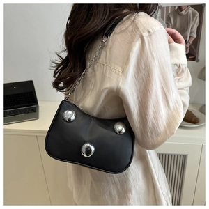 Close-up of black leather shoulder bag with silver metal balls and chain strap detail