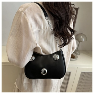 Detail of black leather underarm bag featuring three large silver spherical metal accents