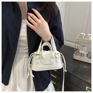Mini white textured shell bag with dual handles and gold brand text in hand