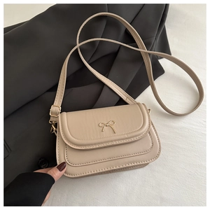 Detailed close-up of cream PU leather shoulder bag with a gold bow-knot metal clasp