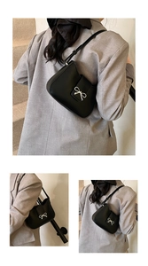Détail du sac sous l'aisselle en cuir noir avec une boucle délicate en nœud argenté