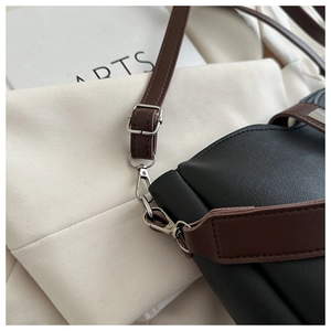 Detail of silver hardware buckle and premium brown leather strap on black bucket bag