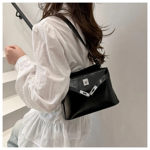 Detail of glossy black leather handbag with silver twist-lock fastener on white stairs