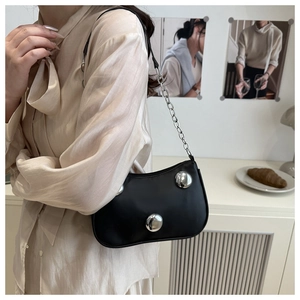 Detail of black crescent shoulder bag with silver dome studs and chain strap on model