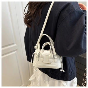 Mini white drawstring crossbody bag worn by a model in a casual indoor setting