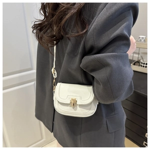 Detailed view of white textured mini crossbody bag with gold buckle on a model