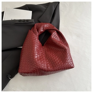 Detail of burgundy woven hobo bag with signature knot handle and premium texture
