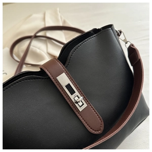 Detail of silver twist-lock closure on black litchi pattern leather bucket bag