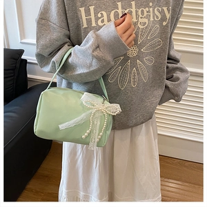 Detailed close-up of mint green mini bag with lace bow and pearl decoration