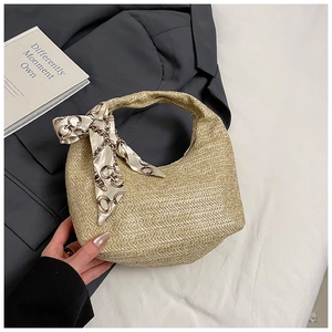 Detail of hand-woven beige straw hobo bag with an elegant silk scarf on the handle