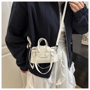 Close-up of mini white pebble leather crossbody bag with drawstring liner and top handles