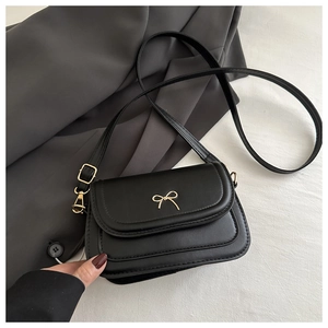 Close-up of golden bow metal buckle on a black PU leather crossbody handbag detail