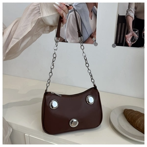 Close-up of brown crescent bag featuring large silver buckles and a metal chain strap