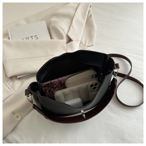 Spacious interior of black bucket bag showing phone, wallet, and inner pocket storage