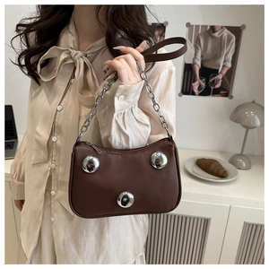 Detail of dark brown leather crescent bag featuring oversized silver metallic globes