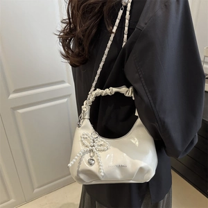 White faux leather shoulder bag with pleated handle, chain strap, and pearl bow charm