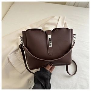 Close-up of dark coffee bucket bag with silver metal twist lock and matte leather finish