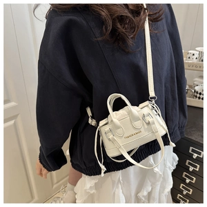 Close-up of mini white Boston bag with litchi texture and crossbody strap details