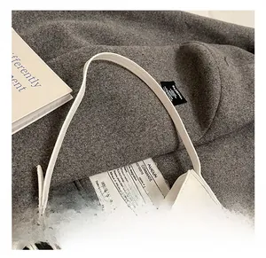 Detail view of white leather crescent bag with silver buckles on dark wool background