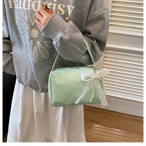 Detail of mint green handbag featuring pearl bow charm and lace trim decoration