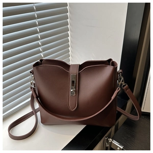 Détail d'un sac seau marron avec fermoir tournant en métal argenté sur un rebord
