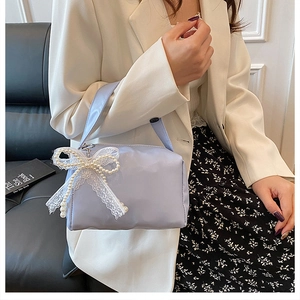 Detail of lavender satin handbag featuring a delicate white lace and pearl bow charm