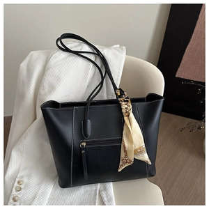 Detail of black tote bag with white contrast stitching and elegant silk scarf on handle