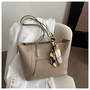 Detail of khaki leather tote bag with functional front zipper and decorative silk scarf