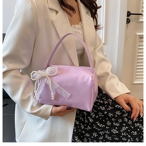 Detail of lavender leather handbag featuring a lace bow and elegant pearl decorations