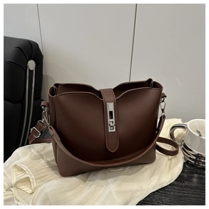 Close-up of brown bucket bag with wavy edge and silver buckle on white fabric