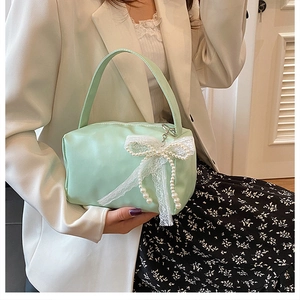 Detail of mint green satin handbag with white lace bow and pearl pendant decoration