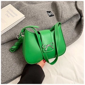 Detail of green leather underarm bag featuring a metallic silver bow clasp and strap