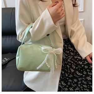 Detail view of light green underarm bag featuring lace pearl bow on a model outfit