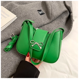 Détail d'un sac sous le bras en cuir vert vif avec une boucle en nœud métallique
