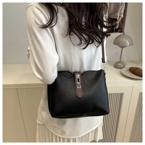 Detail of black faux leather bucket bag with brown strap and silver metal twist lock