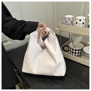 Detail of the white woven leather tote featuring a stylish knotted handle design