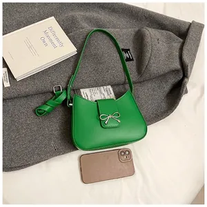 Détail macro d'un sac à bandoulière vert à nœud papillon à côté d'un smartphone pour la taille