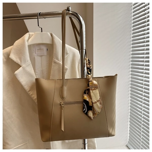 Detail of khaki tote bag with front zipper pocket and decorative patterned silk scarf