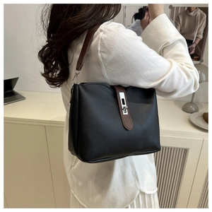 Detail of a chic bucket bag with brown contrast straps and a silver metal turn-lock buckle