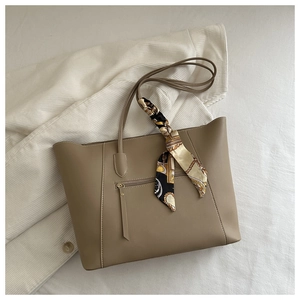 Top view of beige tote bag with decorative silk scarf and stitching on white fabric
