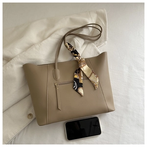 Detail of minimalist tote bag with decorative scarf and functional front zipper pocket