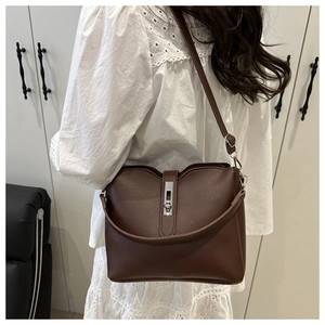 Detail of dark brown leather bucket bag with silver metal buckle and adjustable strap