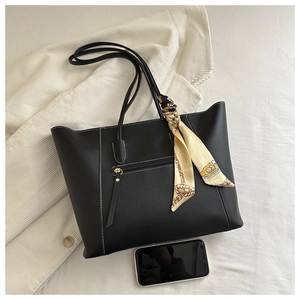 Detail of black leather tote bag with white stitching, silk scarf and smartphone for size