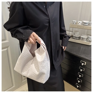 Close-up of white woven leather tote bag with geometric triangular silhouette and soft texture